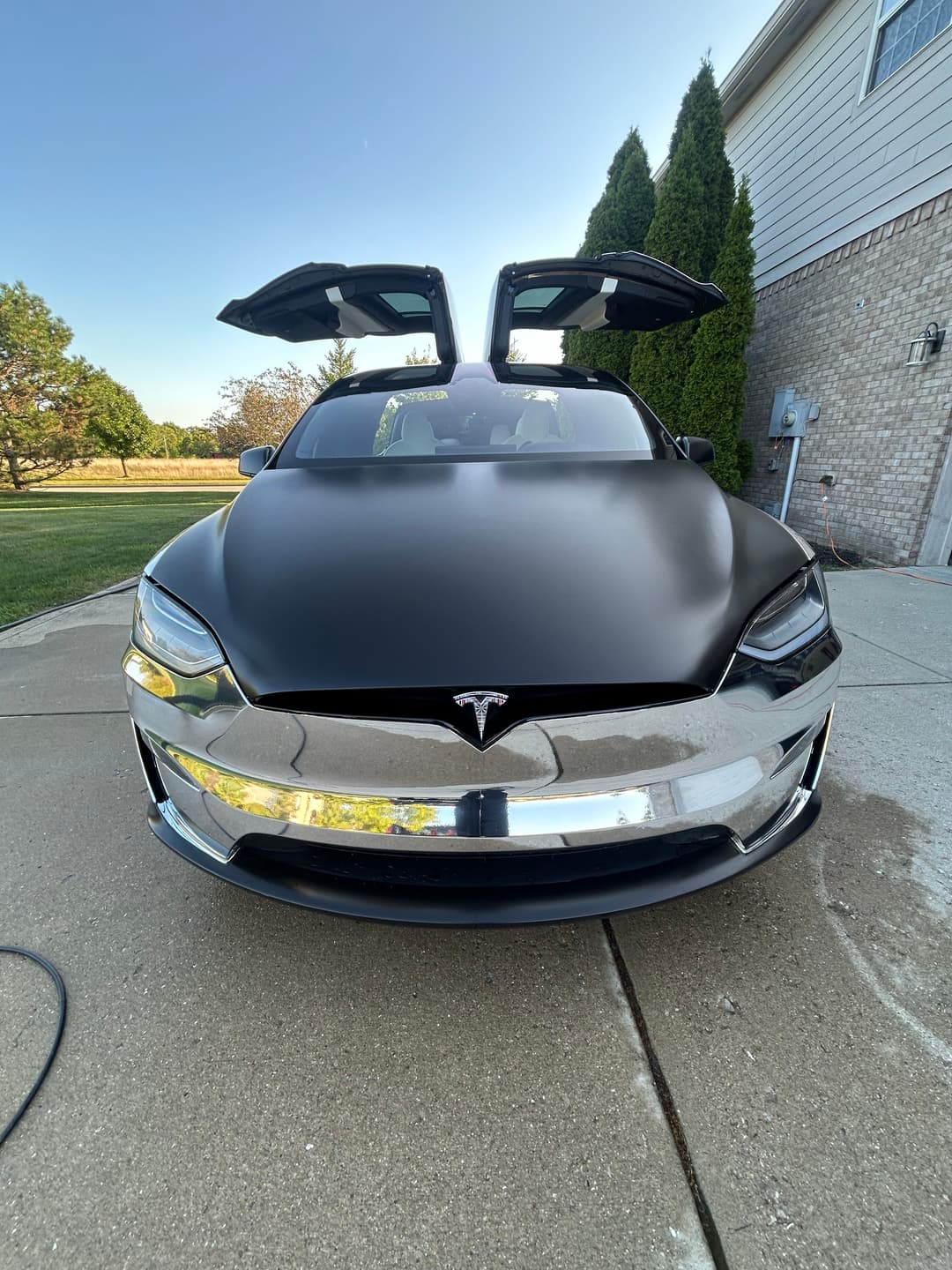 Tesla Model S with sleek black finish and distinctive falcon-wing doors open, parked outdoors.